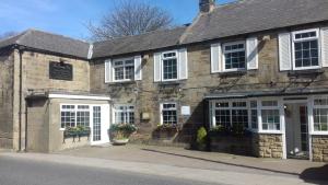 an old stone building with white windows and doors at StoneLaw Cottage in Longframlington