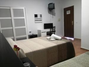 Habitación de hotel con cama y TV en Parrilla Venta el Andaluz, en Conil de la Frontera