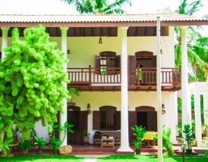 a house with a balcony and a tree at Hotel La Felicita in Mirissa