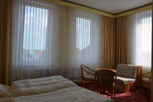 ゾルタウにあるHotel Meynのベッド1台、椅子、窓が備わる客室です。