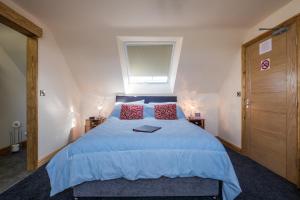 a bedroom with a blue bed with red pillows and a window at Lazy Days in Whitby