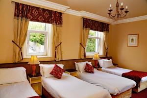 um quarto com três camas e duas janelas em Gabriel House Guesthouse em Cork