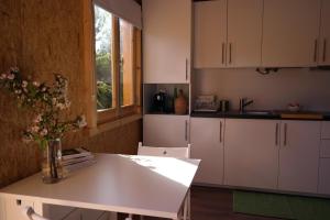 a kitchen with white cabinets and a table with flowers at Casa Batucela in Monte Serrano