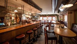 un bar avec des tables en bois et des tabourets de bar dans l'établissement Hotel Kristall, à Sankt Anton am Arlberg