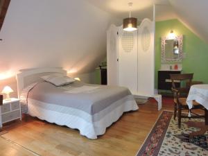 a bedroom with a bed and a table and a chair at Gîte de La Hertaudière in Montbizot