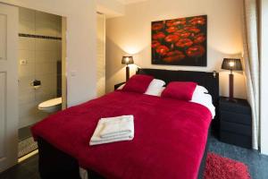 1 dormitorio con cama roja y baño en Baart's Bed and Breakfast, en Wijnandsrade