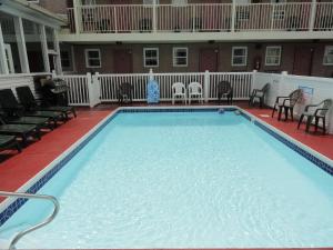 a large swimming pool with chairs and a house at Anchor Motel in Seaside Heights +27 photos