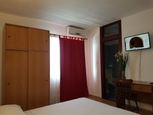 a bedroom with a red curtain and a desk at Bed and Breakfast MIRAMAR in Starigrad