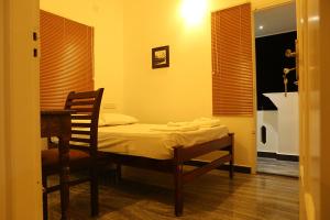 a bedroom with a bed with a chair and a table at Janatha Homestay in Cochin