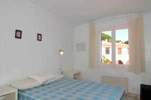 a white bedroom with a bed and a window at Plaça Dels Pous 3 in Pals