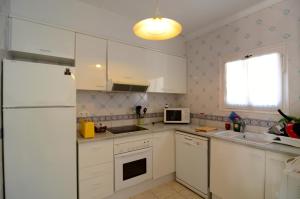 a kitchen with white cabinets and a white refrigerator at Plaça Dels Pous 3 in Pals