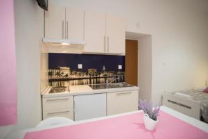 uma cozinha com armários brancos e uma mesa rosa em Summer Bay Apartments em Split