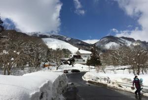 una persona caminando por un camino en la nieve en Hakuba Landmark Happo Lodge, en Hakuba