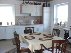 a kitchen with a table and chairs and a kitchen with white cabinets at Ferienwohnung Maier in Kreenheinstetten