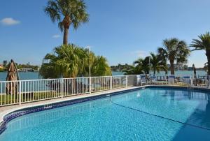 a swimming pool with a fence and palm trees at Westwinds Waterfront Resort in St Pete Beach