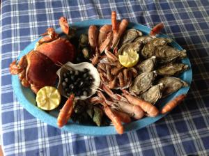 a blue plate of seafood and vegetables on a table at Relais du Cap romain in Saint-Aubin-sur-Mer