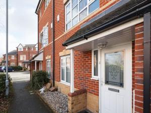 a brick building with a white door on a street at My-Places Abbotsfield Court Townhouse in Manchester