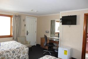 een hotelkamer met een slaapkamer met een bureau en een bed bij Elm Motel in Westfield