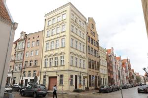 a tall building on a city street with parked cars at Apartament Przy Żurawiu in Gdańsk