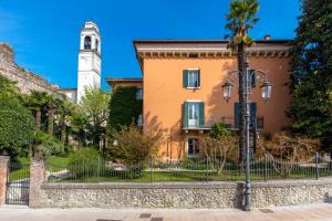 a palm tree in front of a building with a clock tower at CasaBiondani Lazise in Lazise