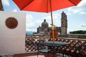 a table with an umbrella on top of a balcony at Hotel Mi Casita in Taxco de Alarcón