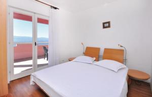 a white bedroom with a bed and a balcony at Apartments Coko in Omiš