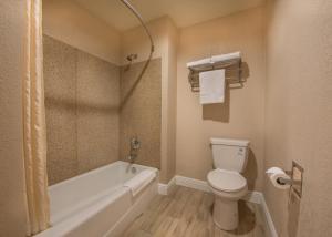 a bathroom with a toilet and a tub and a sink at Edge Water Inn in Reedley