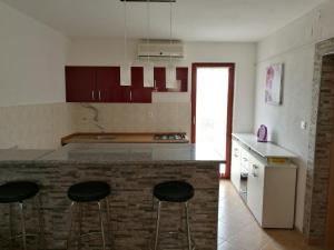 a kitchen with three bar stools at a counter at Apartments Ema Vir in Vir