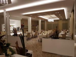 a dining room with white tables and white chairs at Hotel Solemare in Cesenatico