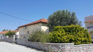 a house with a stone retaining wall and bushes at Filerimos House in Ialyssos