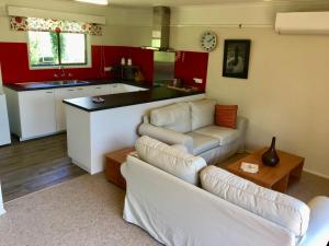 a living room with two white couches and a kitchen at Strathmore Farm B&B in Mirboo North