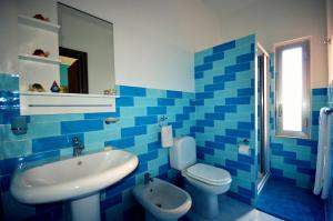 a blue tiled bathroom with a sink and a toilet at Naxos Sea Holiday Apartments in Giardini Naxos +18 photos