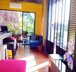 a living room with a couch and chairs and windows at Baan Bida in Krabi