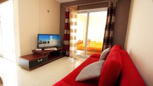 a living room with a red couch and a television at Panikos Beach Apartment I in Larnaca