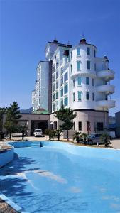 a building with a swimming pool in front of a building at Namhae Beach Hotel in Namhae
