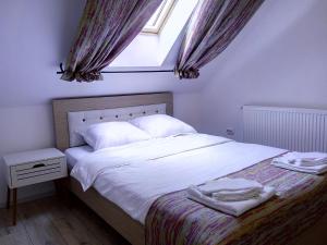 Schlafzimmer mit einem Bett mit weißer Bettwäsche und einem Fenster in der Unterkunft Vila Slanic in Slănic