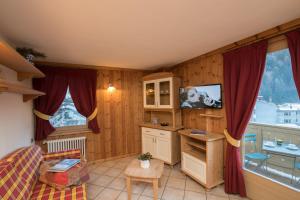a living room with a kitchen with red curtains at Baita Canton in Valfurva