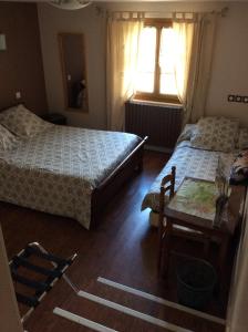 a bedroom with two beds and a table and a window at Auberge des Pyrénées in Sainte-Marie-de-Campan