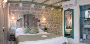 een slaapkamer met een bed en een stenen muur bij Guesthouse Rustico in Dubrovnik