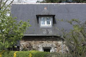 ein Steinhaus mit einem Fenster darüber in der Unterkunft L'herbe des nuits... in Pleyben