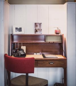a desk with a red chair and a telephone at Henri Hotel Hamburg Downtown in Hamburg