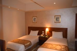 a hotel room with two beds and two lamps at Omar El Khayam Al Minya Hotel - Luxury Accommodation in Minya