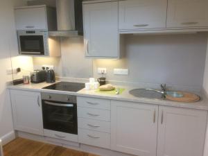 una cocina con armarios blancos y fregadero en Temeside Garden House en Ludlow