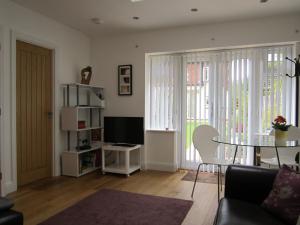 uma sala de estar com uma mesa e uma televisão em Temeside Garden House em Ludlow