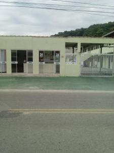 un edificio con una valla blanca delante de él en Hotel Pousada Guaratuba en Guaratuba