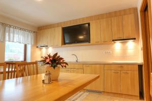 a kitchen with a table and a tv on the wall at Penzion U Bečvy in Karolinka