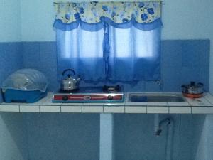 a kitchen counter with a stove and a sink at GELOXEL Angeles City Guesthouse in Angeles