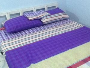 a purple bed with purple sheets and pillows on it at Angeles City Guesthouse in Angeles