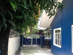 a blue house with a blue gate and a tree at GELOXEL Angeles City Guesthouse in Angeles