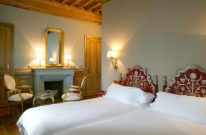 a bedroom with a bed and a fireplace and a mirror at Hotel Castillo de Arteaga in Gautegiz Arteaga